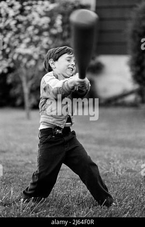 Junge (4-6) bereitet sich darauf vor, den Baseballschläger beim Ball zu schwingen (Schwarzweiß) Stockfoto