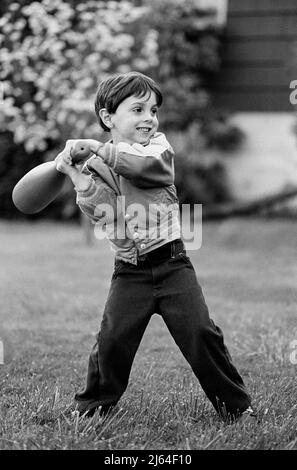 Junge (4-6) bereitet sich darauf vor, den Baseballschläger beim Ball zu schwingen (Schwarzweiß) Stockfoto