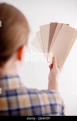 Die junge Frau hält Farbproben für die Wand in der Hand Stockfoto
