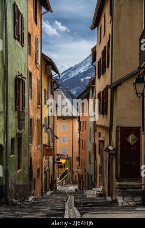 Briancon, Frankreich - 15 Mär 2022: Bunte mittelalterliche Straße in Briancon mit Blick auf den Serre Chevalier; hübscheste Straßen auf Erden Tapete Stockfoto