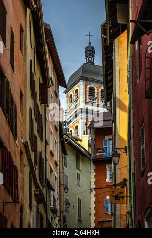 Briancon, Frankreich - 15 Mar 2022: Alte französische Straßendetails mit der Stiftskirche unserer Lieben Frau und dem Heiligen Nikolaus im Hintergrund Stockfoto