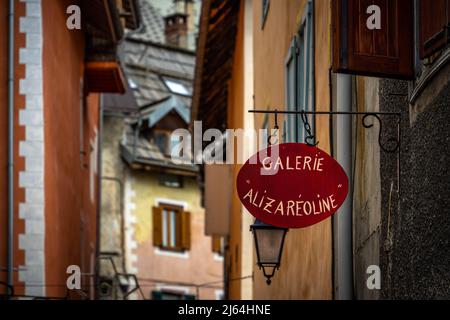 Briancon, Frankreich - 15 Mar 2022: Rotes Holzschild und Detail der Häuser in einer mittelalterlichen Straße von Briancon Stockfoto