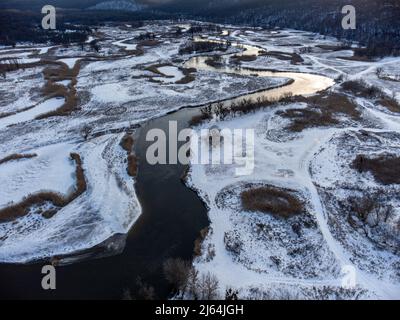 Winter Luftaufnahme ländlichen epischen Blick auf verschneiten Flusstal von Drohne. Region Smijewski auf dem Fluss Siwerskyi Donez in der Ukraine. Kontrastieren Sie die Flusskurve mit der Himmelslinie Stockfoto