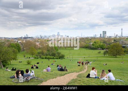 Menschen entspannen sich auf den grasbewachsenen Hängen des Primrose Hill Parks mit freiem Blick auf berühmte Gebäude auf der Londoner Skyline, North London England Stockfoto