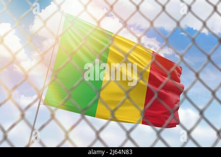 Ein Stahlgeflecht vor dem Hintergrund eines blauen Himmels und einer Fahnenstange mit der Flagge malis Stockfoto