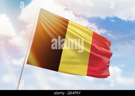 Sonniger blauer Himmel und ein Fahnenmast mit der Flagge belgiens Stockfoto