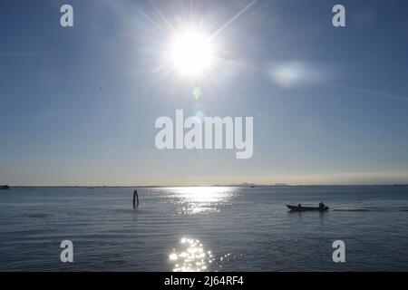 Pellestrina, Italien. 27. April 2022. Ein Boot segelt im Sonnenschein von Pellestrina über das Meer. Pellestrina ist eine Insel und ist Teil der Schließung der Lagune von Venedig zum offenen Meer hin. Quelle: Felix Hörhager/dpa/Alamy Live News Stockfoto