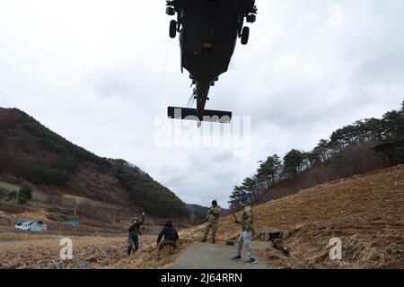 US Air Force 1. LT. Peyton Wilkie, ein Hubschrauber-Pilot der HH-60 Pave Hawk, der der 33. Rescue Squadron, Osan Air Base, zugewiesen wurde, fungiert als ‘isolierte Person’, die während einer gemeinsamen Kampfsuchungs- und Rettungsmission, Pyeongchang, Republik Korea, 31. März 2022, in einen Drehflügelhubschrauber gehisst wird. Piloten und SERE-Instruktoren halfen dabei, sicherzustellen, dass die Operation ordnungsgemäß ausgeführt wurde, um die sichere Extraktion der isolierten Person zu gewährleisten. (USA Armeefoto von Sgt. Oscar Toscano) Stockfoto