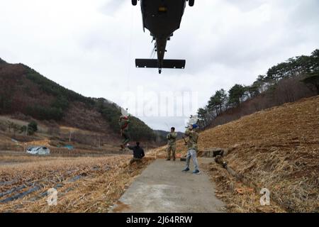 US Air Force 1. LT. Peyton Wilkie, ein Hubschrauber-Pilot der HH-60 Pave Hawk, der der 33. Rescue Squadron, Osan Air Base, zugewiesen wurde, fungiert als ‘isolierte Person’, die während einer gemeinsamen Kampfsuchungs- und Rettungsmission, Pyeongchang, Republik Korea, 31. März 2022, in einen Drehflügelhubschrauber gehisst wird. Piloten und SERE-Instruktoren halfen dabei, sicherzustellen, dass die Operation ordnungsgemäß ausgeführt wurde, um die sichere Extraktion der isolierten Person zu gewährleisten. (USA Armeefoto von Sgt. Oscar Toscano) Stockfoto