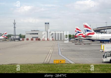 London, Großbritannien - 19. April 2022: Blick auf ein Industriestützgebäude mit Schornsteinen neben den Hauptgebäuden des Terminals 5 mit British Airways Stockfoto