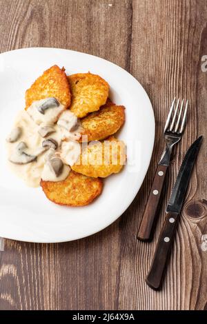 Pfannkuchen mit gebratenen Pilzen und Zwiebeln. Kartoffelpfannkuchen mit Pilzen und Sauerrahm. Ukrainische Küche, europäische Küche. Stockfoto