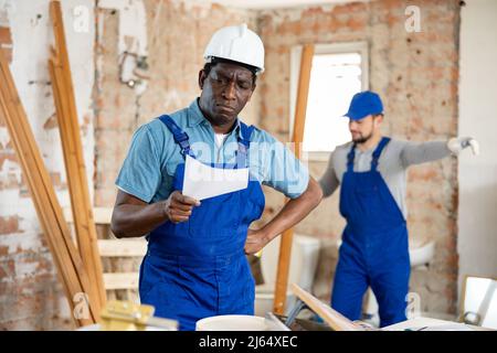 Vorarbeiter unzufrieden mit der Qualität der Reparaturarbeiten des männlichen Bauherrn Stockfoto