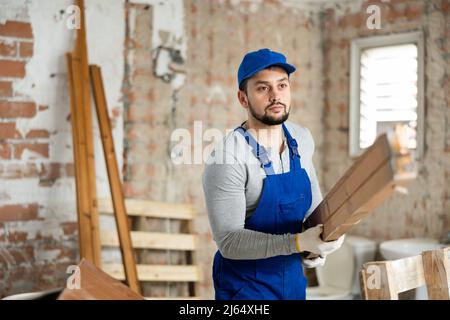 Mann, der Holzmaterialien auf der Baustelle trägt Stockfoto