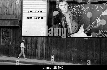 Schild zum Gedenken an den Tod von John Lennon im Jahr 1980 neben einer Plakatwand für Rod Stewart an der Seite des Licorice Pizza Plattenladens am Sunset Strip. Stockfoto