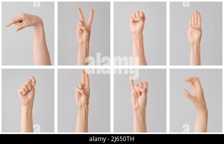 Hände mit verschiedenen Buchstaben auf grauem Hintergrund. Zeichen-Alphabet Stockfoto