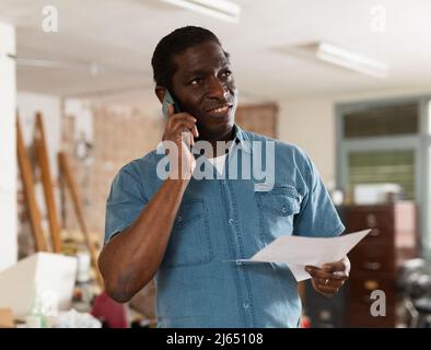 Mann, der auf der Baustelle telefonische Gespräche führt Stockfoto