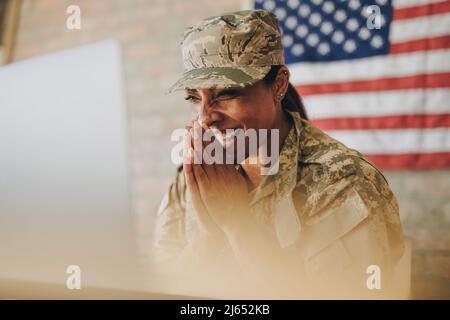 Fröhliche Soldatinnen lächeln fröhlich, während sie ihre Familie auf einem Laptop anrufen. Amerikanische Militärangehörende, die mit ihren Angehörigen kommunizierte, während Serv Stockfoto