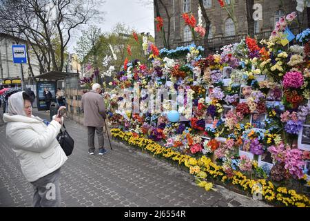 Eine Frau macht Fotos von Menschen, die von Russen wegen einer russischen Militärinvasion in die Ukraine an der „Mauer der Erinnerung“ in Lemberg getötet wurden. Der Amerikaner Leo Soto, der Gründer der gemeinnützigen Organisation „Wall of Hope“ Foundation, kam eigens in die Ukraine und schuf eine „Wall of Memory“ auf einer der Straßen von Lemberg. Er fand Fotos von russischen Opfern im Internet und druckte sie aus. Er schmückte die Wand mit Fotos von künstlichen Blumen. Auf diese Weise wollte er die unschuldigen Opfer der russischen militärischen Aggression in der Ukraine ehren. (Foto von Pavlo Palamarchuk/SOPA Images/Sipa USA) Stockfoto