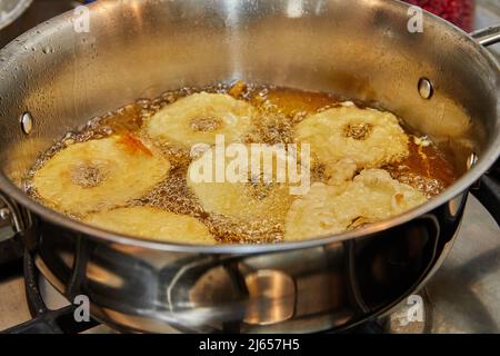 Kochen von Apfelpfannkuchen. Apfeldonut in kochendem Öl. Stockfoto