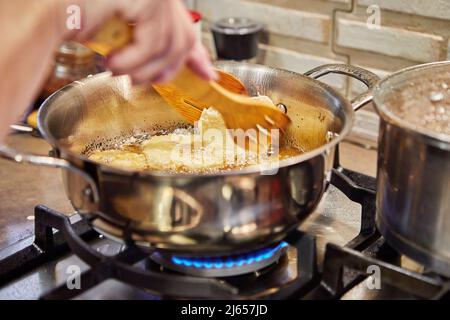 Kochen von Apfelpfannkuchen. Der Küchenchef dreht den Apfeldonut in das kochenden Öl. Stockfoto