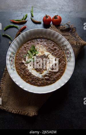 Dal makhni oder dal makhani ist ein nordindisches Rezept, das schwarze Linsen und rote Nierenbohnen in einer Schüssel auf dunklem Grund verwendet. Draufsicht. Stockfoto