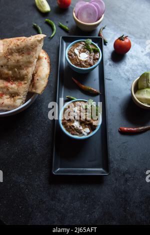 Indische Speisekarte Kabuli Naan oder Fladenbrot zusammen mit schwarzer Linsensuppe. Nahaufnahme, selektiver Fokus. Stockfoto