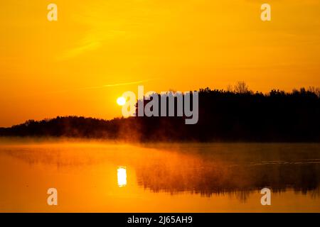 Hannover, Deutschland. 28. April 2022. Die Sonne geht über dem Altwarmbüchensee auf, während Bodennebel über die Wasseroberfläche driftet. Quelle: Moritz Frankenberg/dpa/Alamy Live News Stockfoto
