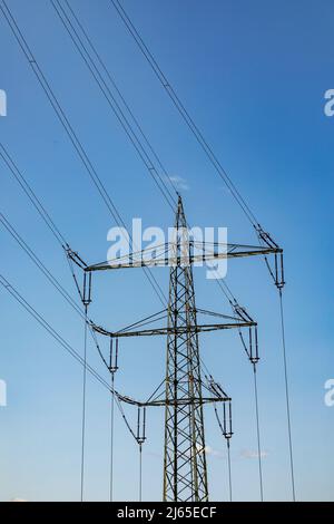 Elektrischer Mast für die Stromverteilung unter klarem blauen Himmel Stockfoto