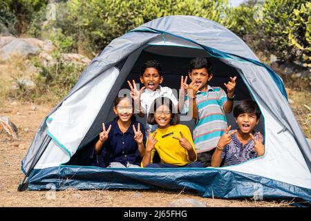 Gorup von Kindern in Camping Zelt Grimacing durch Blick auf die Kamera während Sommercamp der Hügelspitze - concpet von Glück, Entspannung und Urlaub Stockfoto