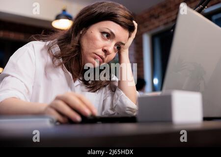 Müde Mitarbeiter des Unternehmens sitzen am Schreibtisch im Büro Arbeitsplatz, während sie unter Müdigkeit wegen Überstunden. Erschöpfter Leiharbeiter, der an Burnout-Syndrom und Migräne leidet. Stockfoto