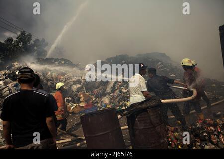 Mitglieder der Feuerwehrmannschaft von Jakarta und lokale Personen, die die Abkühlphase durchführten, nachdem ein Feuerunfall Lagergebäude einer Heimindustrie in Kebayoran Lama, Süd-Jakarta, Jakarta, Indonesien, niedergebrannt hatte. Stockfoto