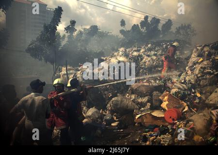 Mitglieder der Feuerwehrmannschaft von Jakarta und lokale Personen, die die Abkühlphase durchführten, nachdem ein Feuerunfall Lagergebäude einer Heimindustrie in Kebayoran Lama, Süd-Jakarta, Jakarta, Indonesien, niedergebrannt hatte. Stockfoto