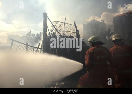Mitglieder der Löschgruppe von Jakarta, die die Abkühlphase nach einem Feuerunfall durchführten, verbrannten Lagergebäude einer Heimindustrie in Kebayoran Lama, Süd-Jakarta, Jakarta, Indonesien. Stockfoto