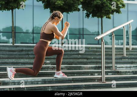 Athletische Frau beim Ausfallschritt während ihres Street Workout Stockfoto