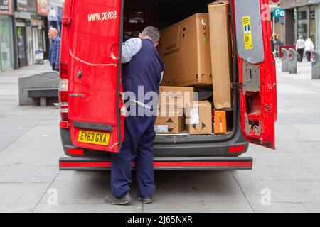 Vollbeladene Express-Paketzustellung (Parcelforce Worldwide). Postbote für Royal Mail-Fahrzeug mit zerbrechlichen Paketen, „This Way Up“-Kartons, die in Southport, Großbritannien, geliefert werden Stockfoto