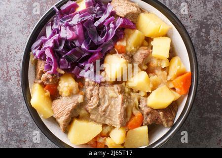 Scouse ist ein Eintopf mit Fleisch und Gemüse, serviert mit eingelegtem Kohl aus nächster Nähe auf einem Teller auf dem Tisch. Horizontale Draufsicht von oben Stockfoto