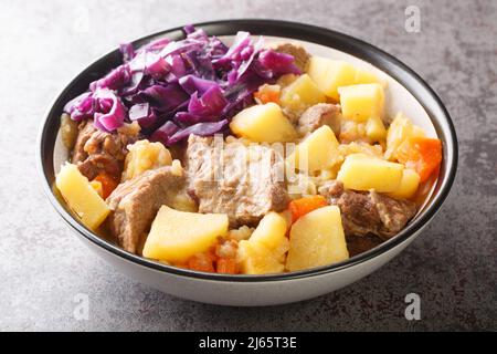 Scouse ist ein Eintopf mit Fleisch und Gemüse, serviert mit eingelegtem Kohl aus nächster Nähe auf einem Teller auf dem Tisch. Horizontal Stockfoto