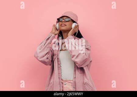 Monochromes Porträt von jungen attraktiven glückliche Frau in lässigen Stil Outfit hören Musik isoliert auf rosa Hintergrund. Konzept der Schönheit, Kunst Stockfoto