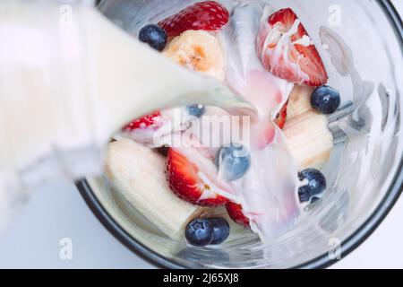 Smoothie oder Milchshake im Mixer zubereiten. Milch in einen Mixer mit Früchten gießen. Veganer Smoothie mit Mandelmilch Stockfoto