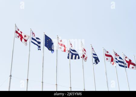 Die Flaggen Georgiens und der Europäischen Union winken im Wind gegen den Himmel Stockfoto