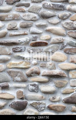 Felswand aus natürlichen Flusssteinen. Wand runde Felsstruktur und nahtloser Hintergrund, Bürgersteig Stockfoto