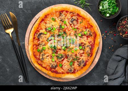 Hausgemachte Pizza mit Käse, Pilzen, Tomaten und frischen Kräutern auf dunklem Hintergrund. Vegetarische Gerichte. Draufsicht, Nahaufnahme. Stockfoto