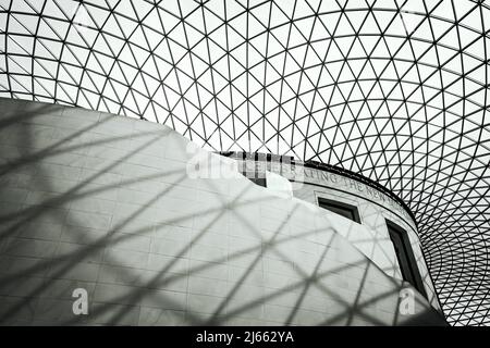 London, Großbritannien - 18. April 2022: Das Innere des British Museum in London, das einen Abschnitt des Großen Hofes mit Treppe und geometrischem Dach zeigt. Op Stockfoto