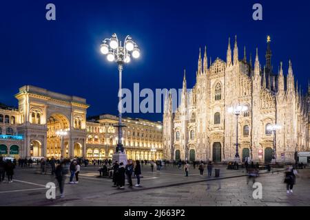 Die Menschen genießen die Piazza del Duomo, dominiert von der Fassade der Kathedrale und dem Eingang der Galerie Vittorio Emanuele II bei Nacht in Mailand, Italien. Stockfoto
