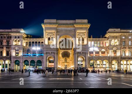 Vorderansicht des Triumphbogens Eingang der Galleria Vittorio Emanuele II verglaste Einkaufspassage in der Piazza del Duomo bei Nacht in Mailand, Italien Stockfoto
