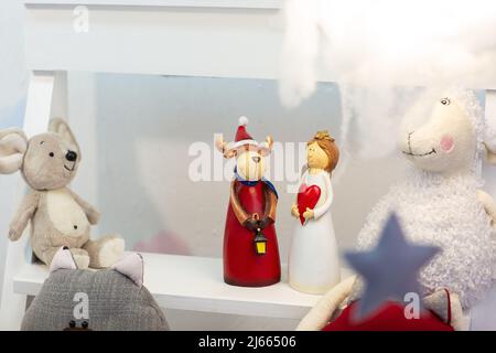 Weihnachten Keramik Spielzeug Hirsch und Engel in Feiertagskleidung auf Holzschlitten unter Schnee, verschwommener Hintergrund Stockfoto