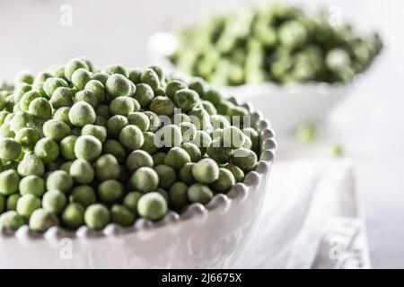 Gefrorene Erbsen in einer weißen Porzellanschüssel - Close Up. Stockfoto