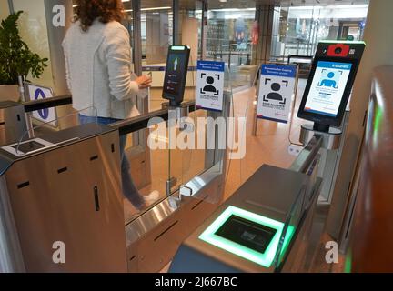 Hamburg, Deutschland. 28. April 2022. Eine Frau geht am biometrischen Gesichtserkennungssystem vor der Sicherheitskontrolle im Abflugbereich des Hamburger Flughafens vorbei. Der neue Service steht Star Alliance-Passagieren (Österreich, Schweiz und Lufthansa) zur Verfügung, die am Miles & More Treueprogramm teilnehmen. Passagiere erhalten kontaktlosen Zugang zum Sicherheitskontrollpunkt und zum Boarding. Eine Bordkarte oder ein Smartphone müssen nicht mehr vorgelegt werden. Kredit: Marcus Brandt/dpa/Alamy Live Nachrichten Stockfoto