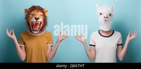 Junge Frau in Löwe und Alpaka Maske mit erhobenen Händen in Meditation Yoga Mudra Zeichen, isoliert auf blauem Hintergrund Stockfoto