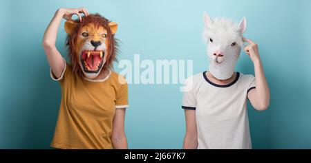 Junge Frau in Löwe und Alpaka-Maske denkend, kratzt ihren Kopf, isoliert auf blauem Hintergrund Stockfoto